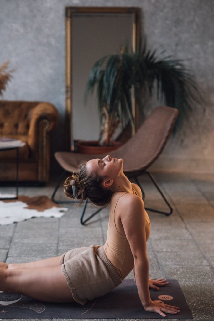 a woman in brown tank top stretching on a yoga mat